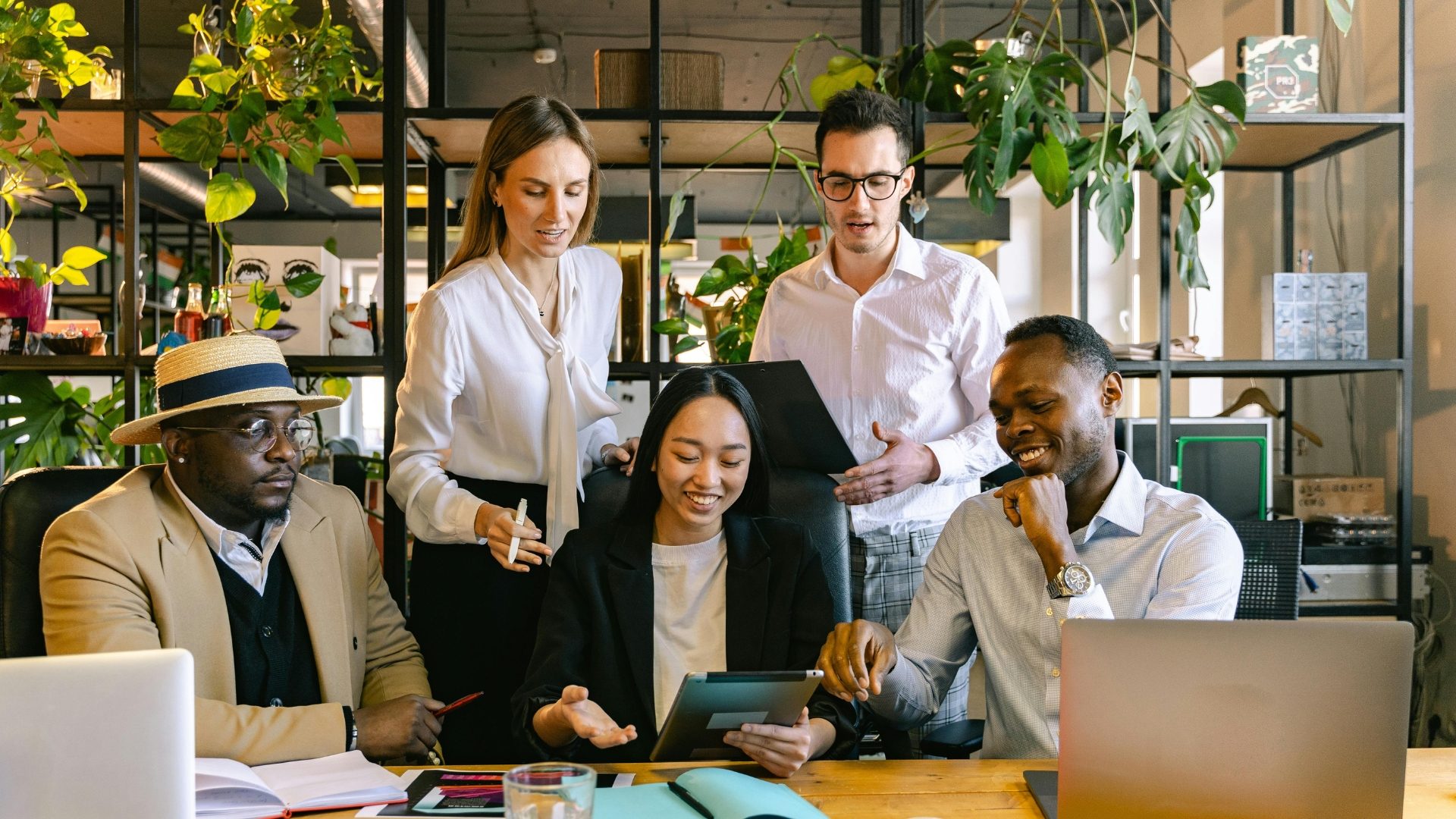 A team of colleagues collaborating around a tablet in a bright office